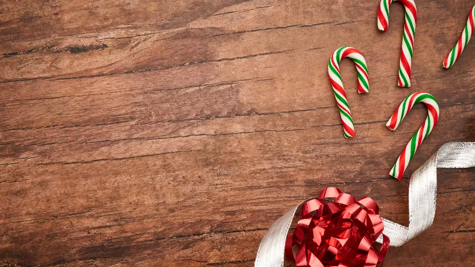 Bastones de caramelo pequeños junto a un lazo rojo